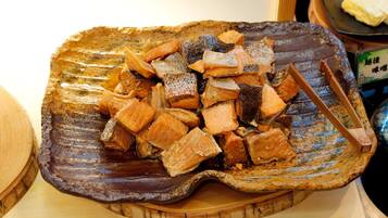 A ceramic dish with various types of fish, including salmon and other varieties, arranged on a wooden board.