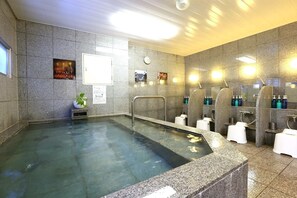 Un área de piscina interior con paredes de piedra, un reloj y un cuadro en la pared.