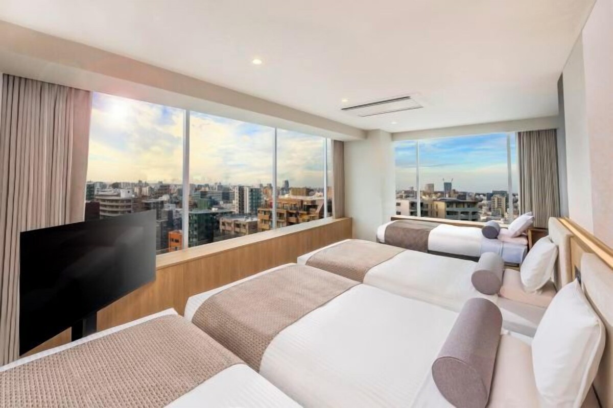 Hotelkamer met uitzicht over de stad, twee bedden, een televisie en een groot raam.
