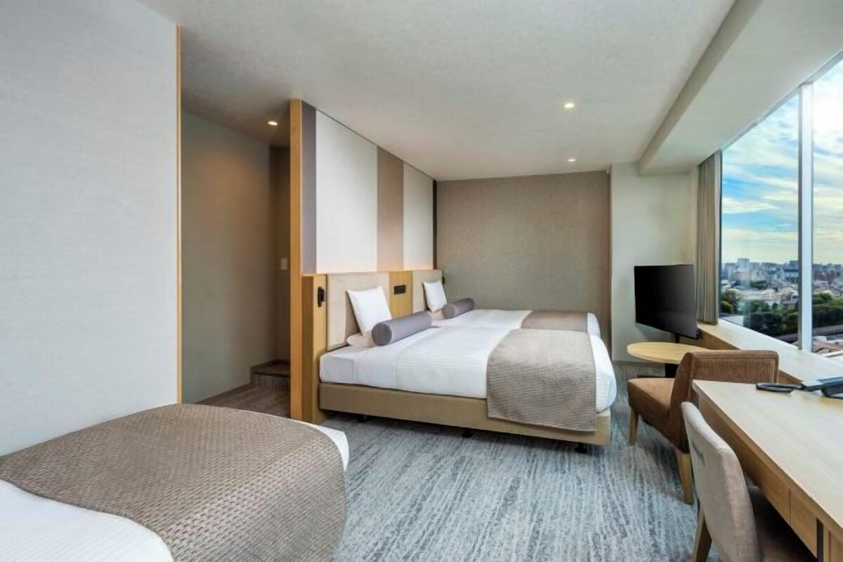 Una habitación de hotel moderna con una cama grande, un escritorio y un televisor.