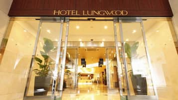 A hotel entrance with a sign reading 'HOTEL LUNGWOOD' and a green carpet leading to the doors.