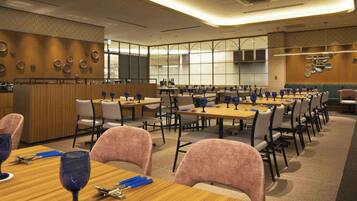 A hotel dining area with multiple tables, chairs, and a bar area.