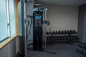 A gym with a cable machine, dumbbells, and a bench. - Hotel Lungwood (Tokyo)