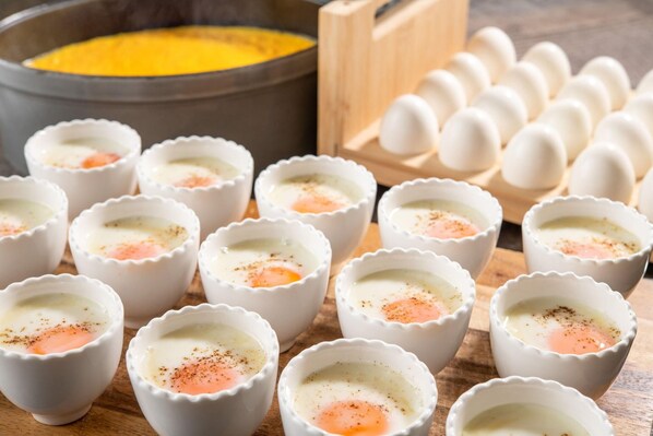Una colección de recipientes pequeños con huevos pochados, una olla con mezcla amarilla y un cartón de huevos.