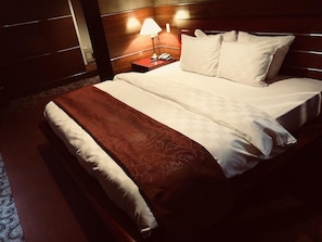 A hotel room with a large bed, a bedside table with a lamp, and a wooden headboard. - King Ambassador Hotel Kumagaya (Kumagaya)