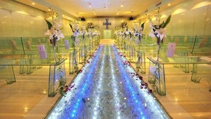 An indoor venue with a central aisle, glass railings, and floral arrangements. - King Ambassador Hotel Kumagaya (Kumagaya)