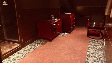 Una habitación con alfombra estampada, un aparador rojo, una silla y una puerta de madera.