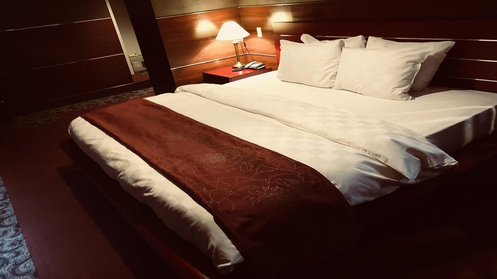 Una habitación de hotel con una cama, una mesita de noche y una lámpara.