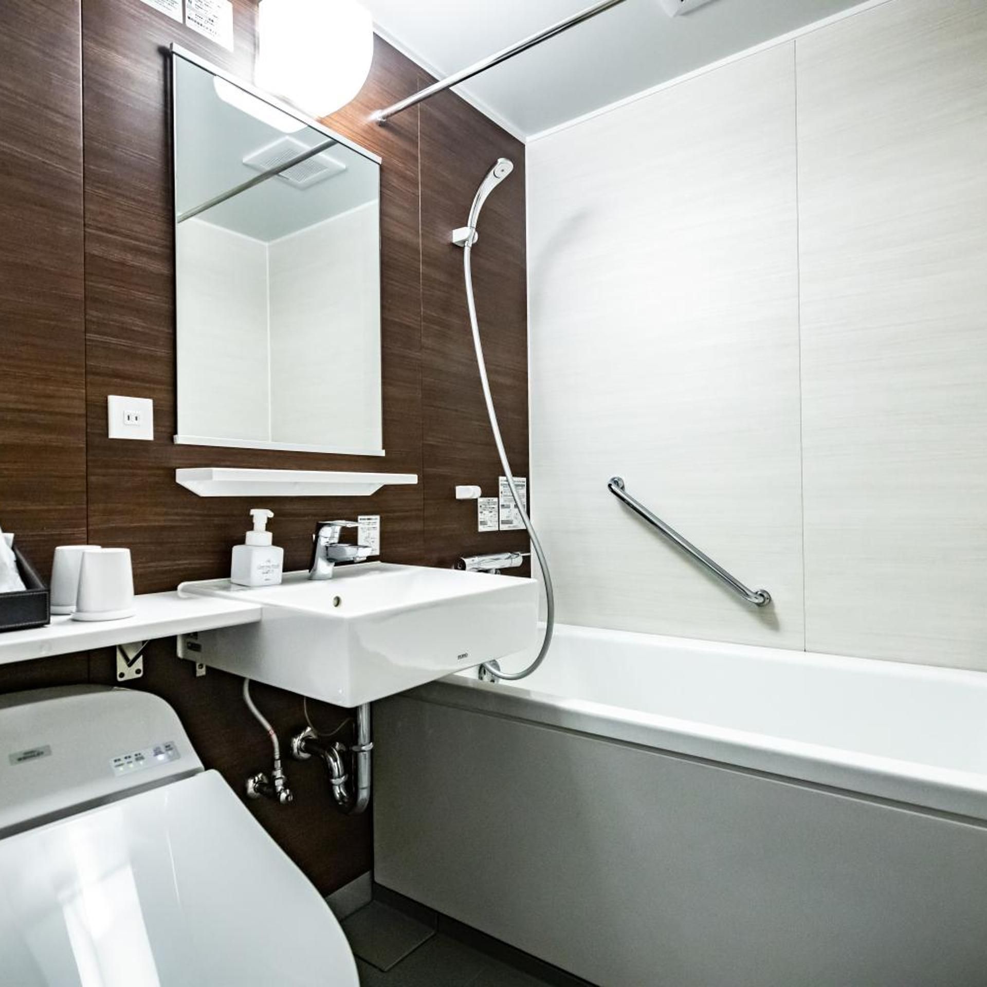 Une salle de bain moderne avec un lavabo blanc, un miroir et une douche.