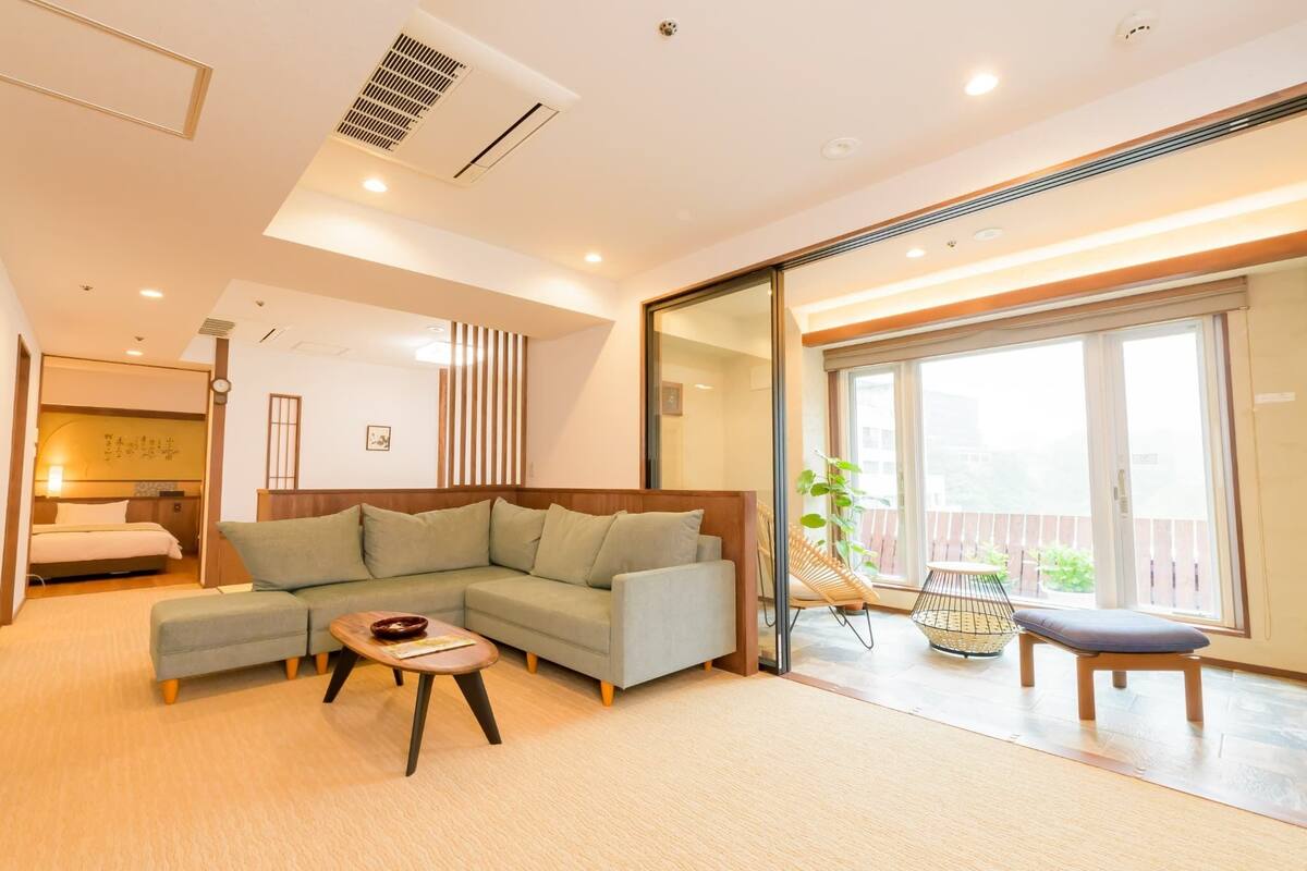 A modern living room with a sectional sofa, a small table, and a sliding glass door leading to a balcony.