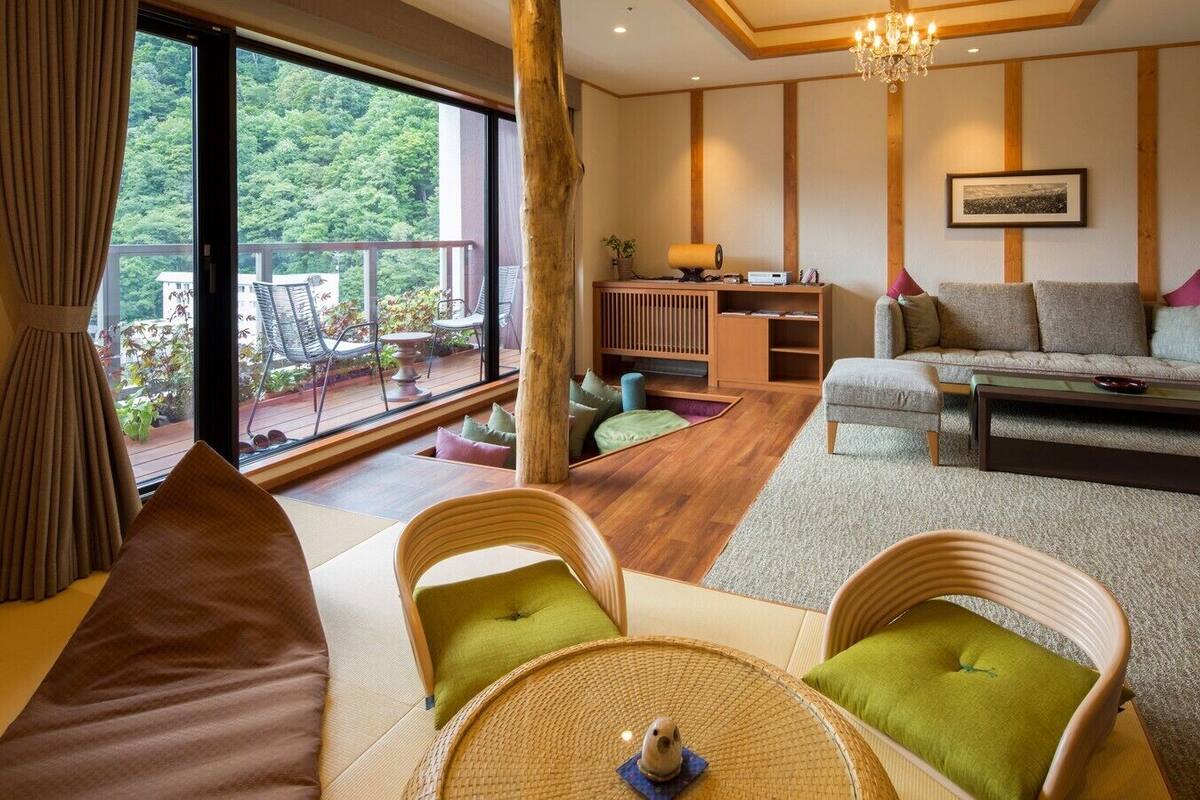 A living room with a sofa, chairs, a coffee table, a fireplace, and a balcony with outdoor furniture.