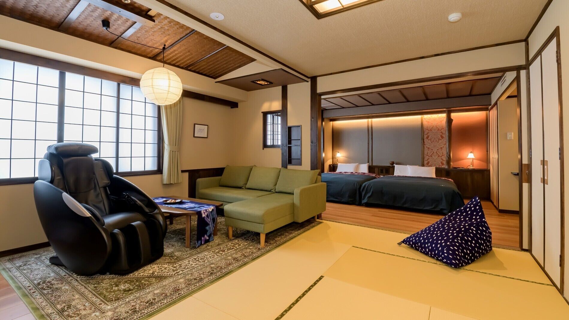 Perinteinen japanilaistyylinen huone, jossa on tatamimatto, futon-patja, hierontatuoli ja matala pöytä, jonka päällä on pieni pöytäliina.