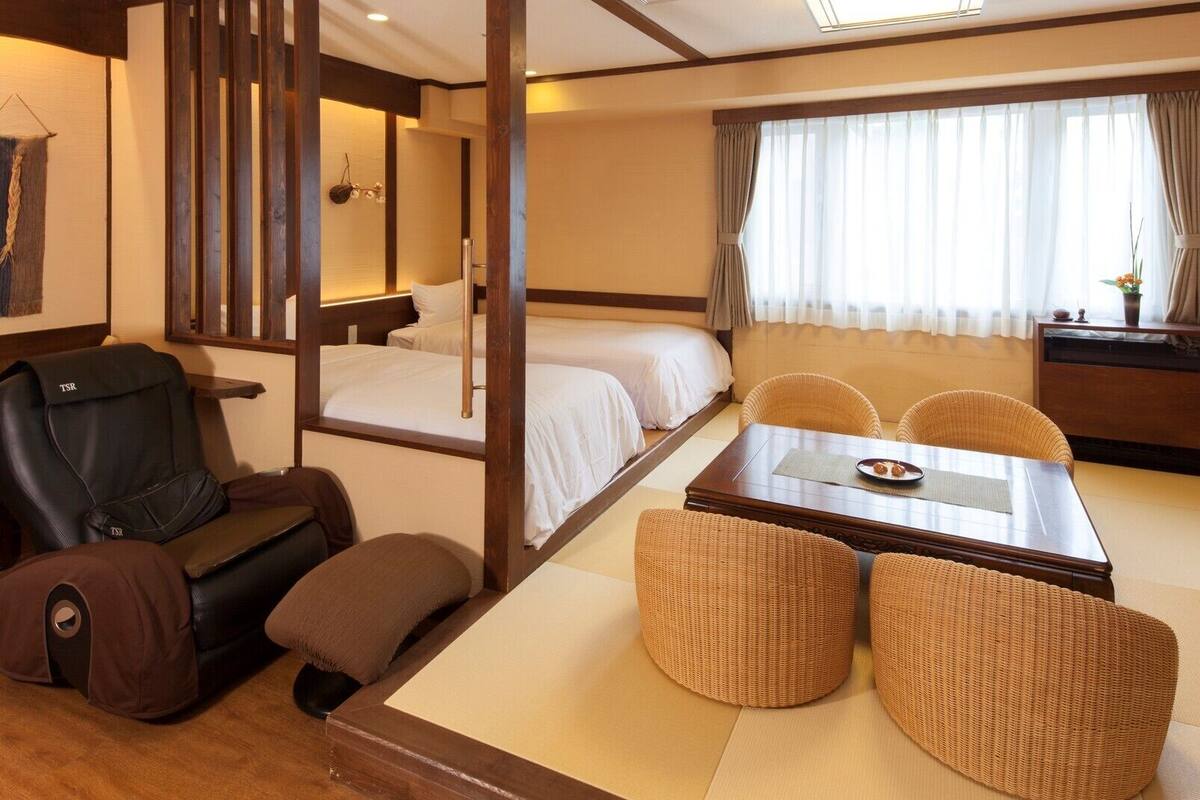 A hotel room with a bed, a sofa, a dining table, and a chair.