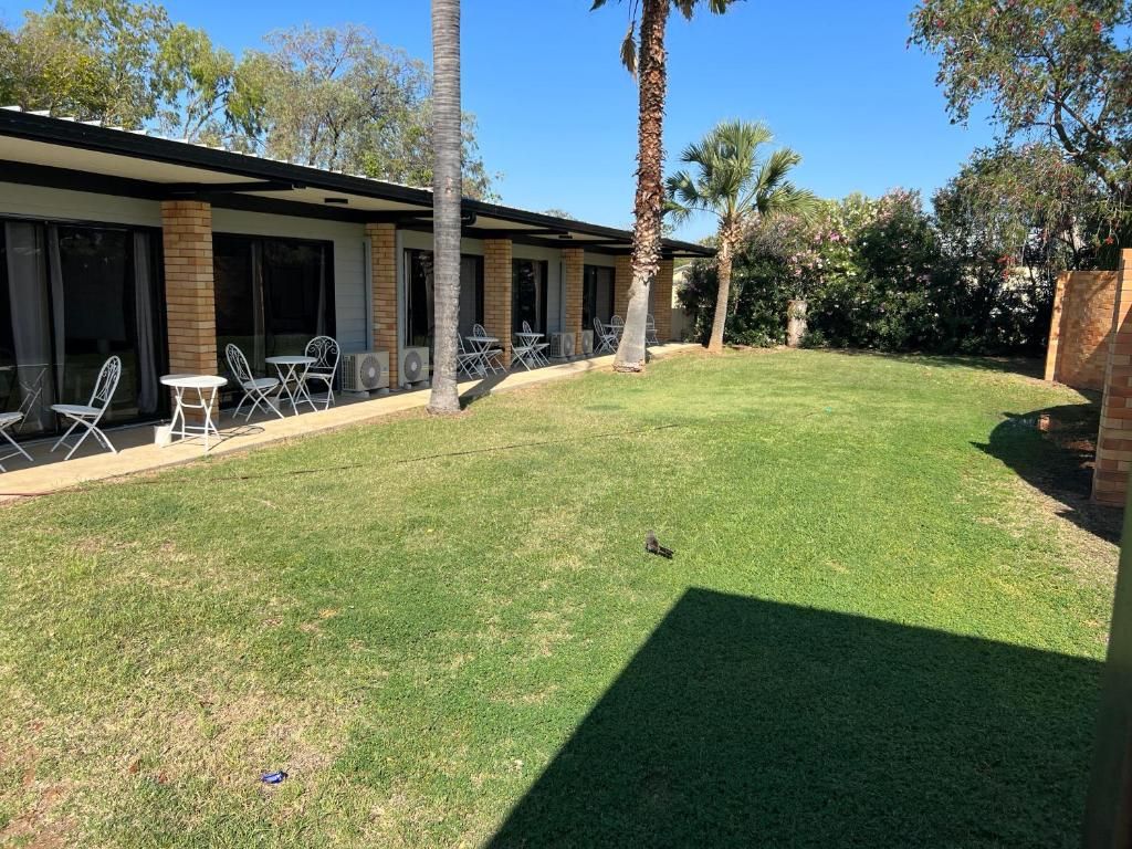 A building with a covered patio area, outdoor seating, and a well-maintained lawn.