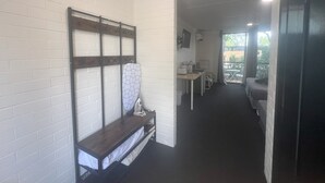 A narrow hallway with a bench, a small table, and a TV mounted on the wall. - Jumbuck Motel (Longreach)