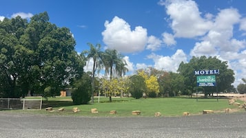 Jumbuck Motel offers a pool and BBQ facilities, surrounded by a well-maintained lawn with trees.