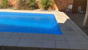 Una piscina con bordo piastrellato, circondata da un muro in mattoni con decorazioni raffiguranti animali.
