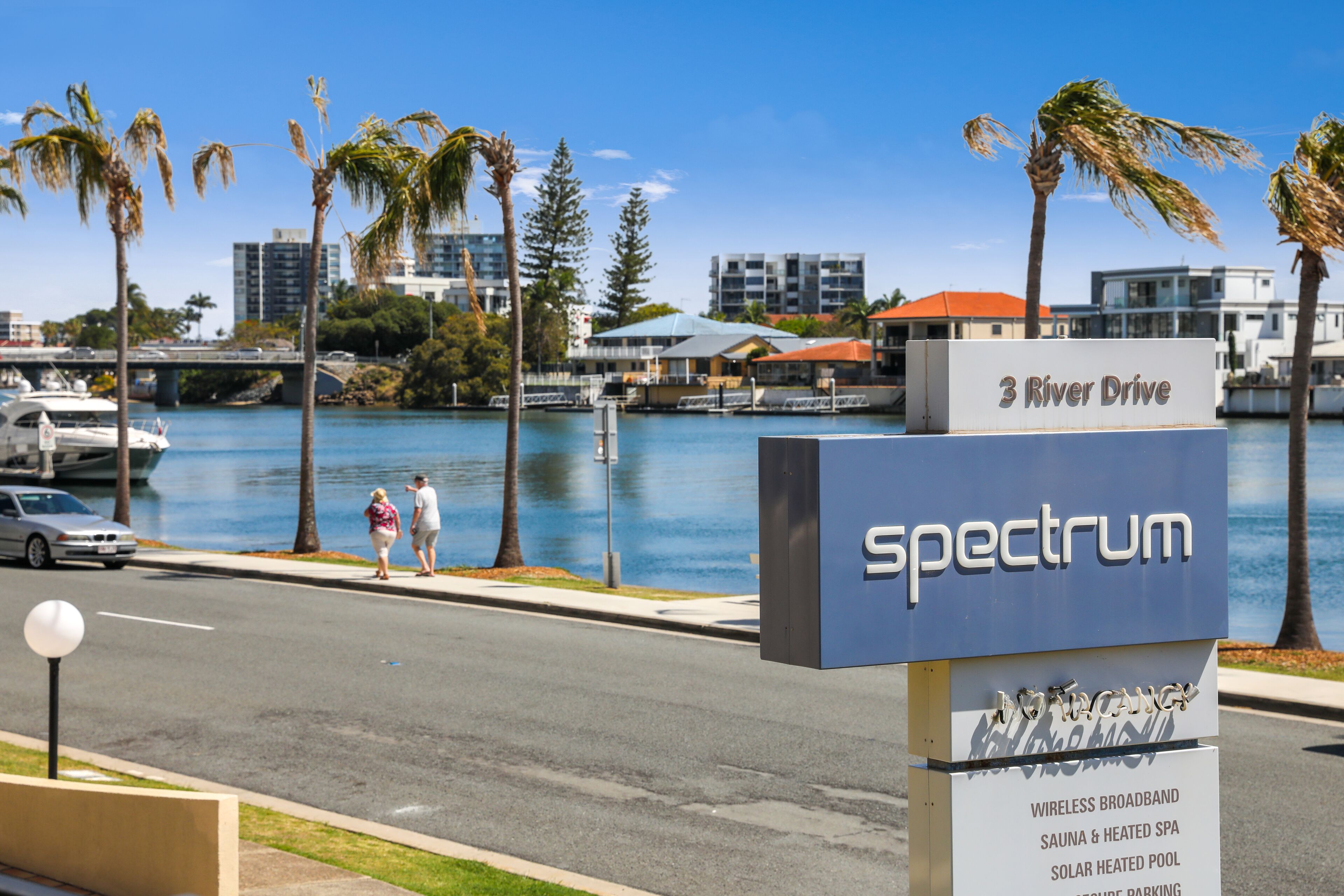 A sign for Spectrum at 3 River Drive, listing amenities like wireless broadband, sauna, heated spa, solar heated pool, and parking.