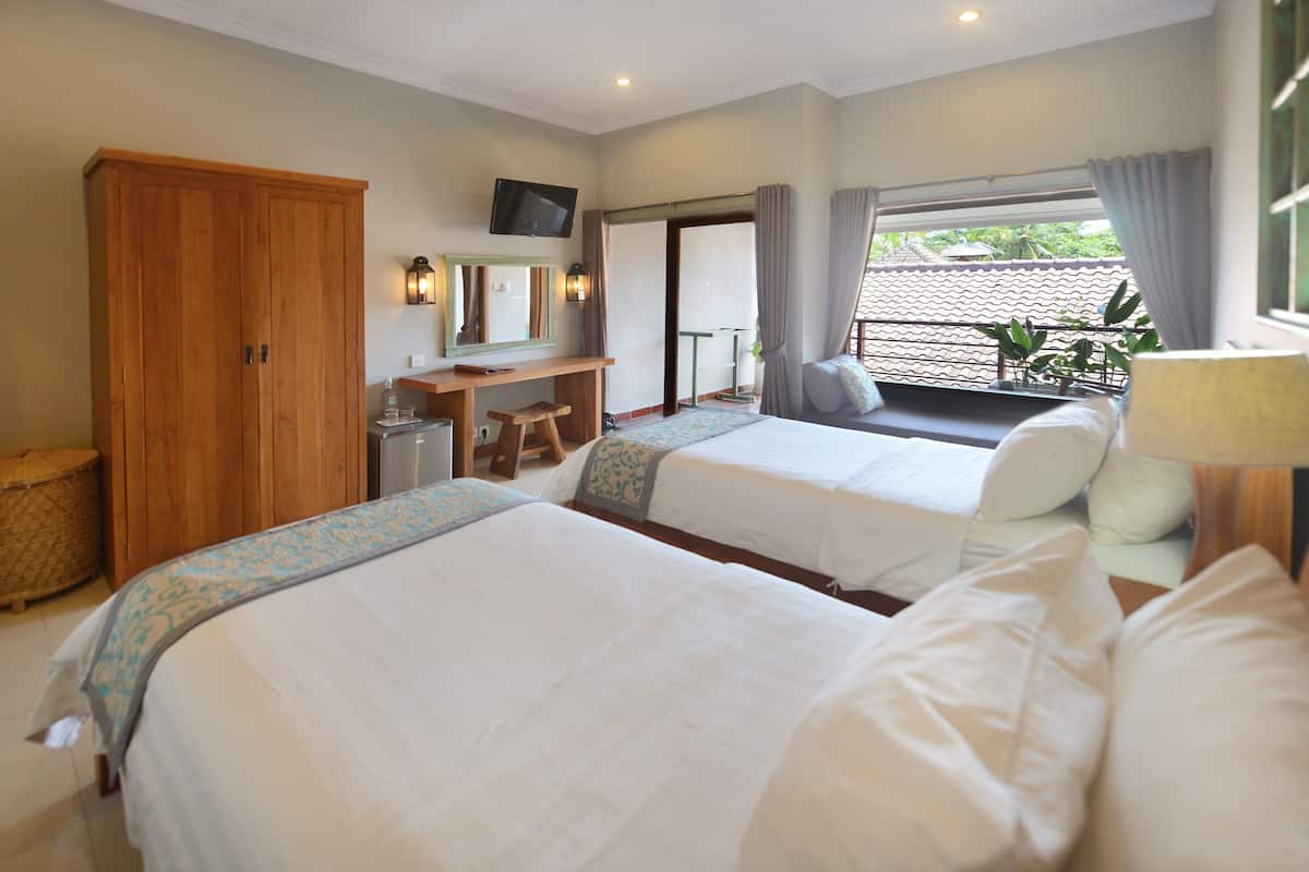 Ein Hotelzimmer mit zwei Betten, einem Schreibtisch, einem Fernseher und einem Balkon mit Blick.
