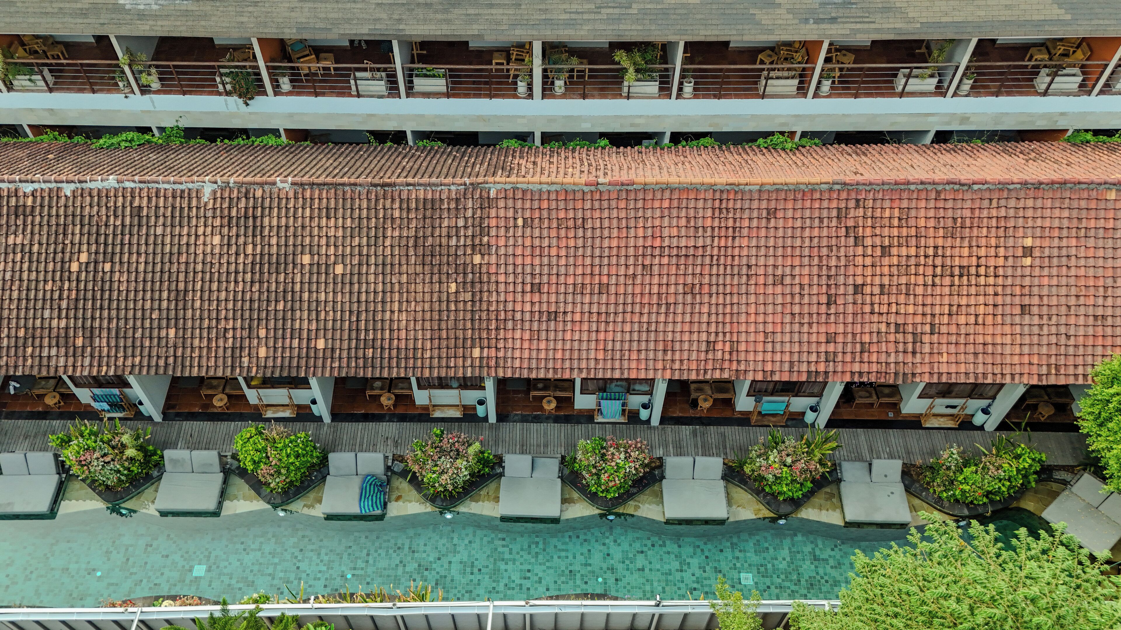 A rooftop pool area with multiple lounge chairs and a tiled roof.
