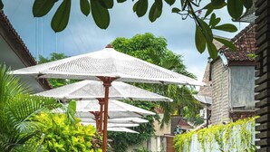 A pool area with lounge chairs and umbrellas. - Trawangan Dive Centre (Gili Trawangan)