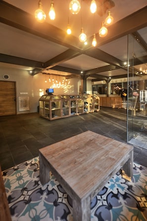 A spacious lobby with a wooden bench, a glass display case with shoes, and hanging light fixtures. - Trawangan Dive Centre (Gili Trawangan)