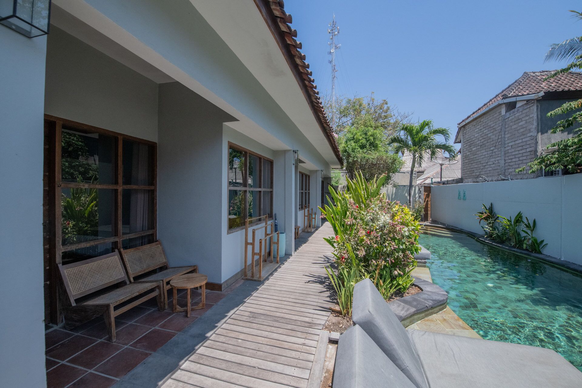 Zona de piscina con una terraza de madera, un banco y una pequeña mesa.