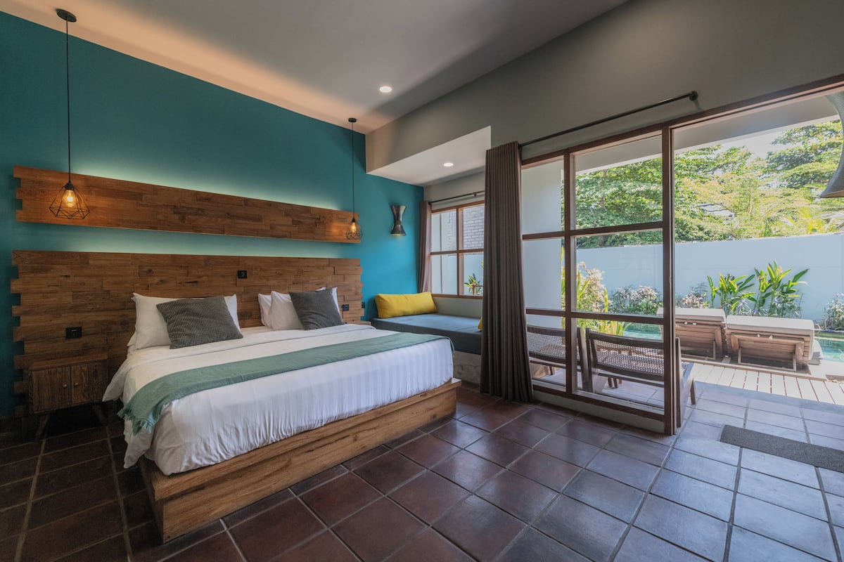 Ein Schlafzimmer mit einem hölzernen Bett, Blick ins Freie und einem großen Fenster.