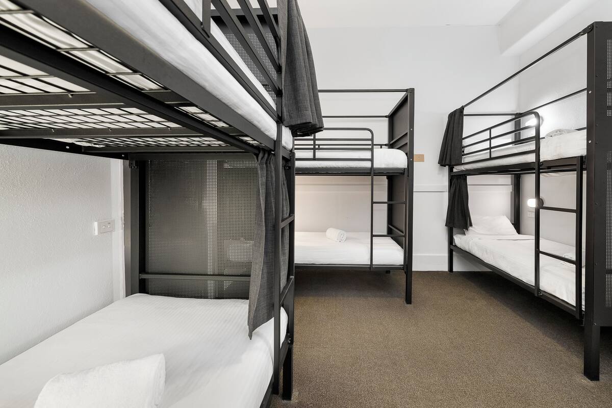 Quarto com beliches, piso coberto por carpete e janela com persianas.