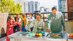 A group of people preparing food outdoors with a cityscape in the background. - YHA Melbourne Central (Melbourne)