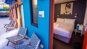 A hotel room with a bed, a nightstand, a wall clock, and a window. - YHA Melbourne Central (Melbourne)