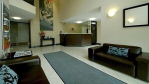 Een moderne lobby met een receptiebalie, een bank en een salontafel.