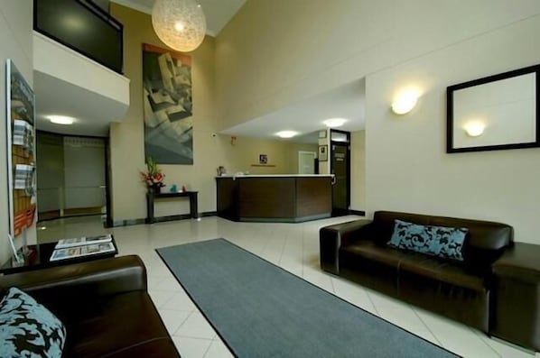 A modern lobby with a reception desk, a sofa, and a coffee table.