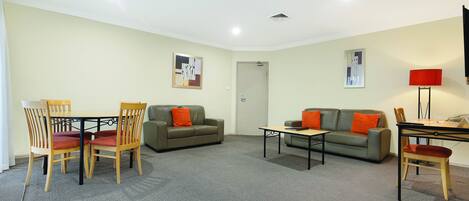 A furnished living room with a sofa, two chairs, a coffee table, and a TV.