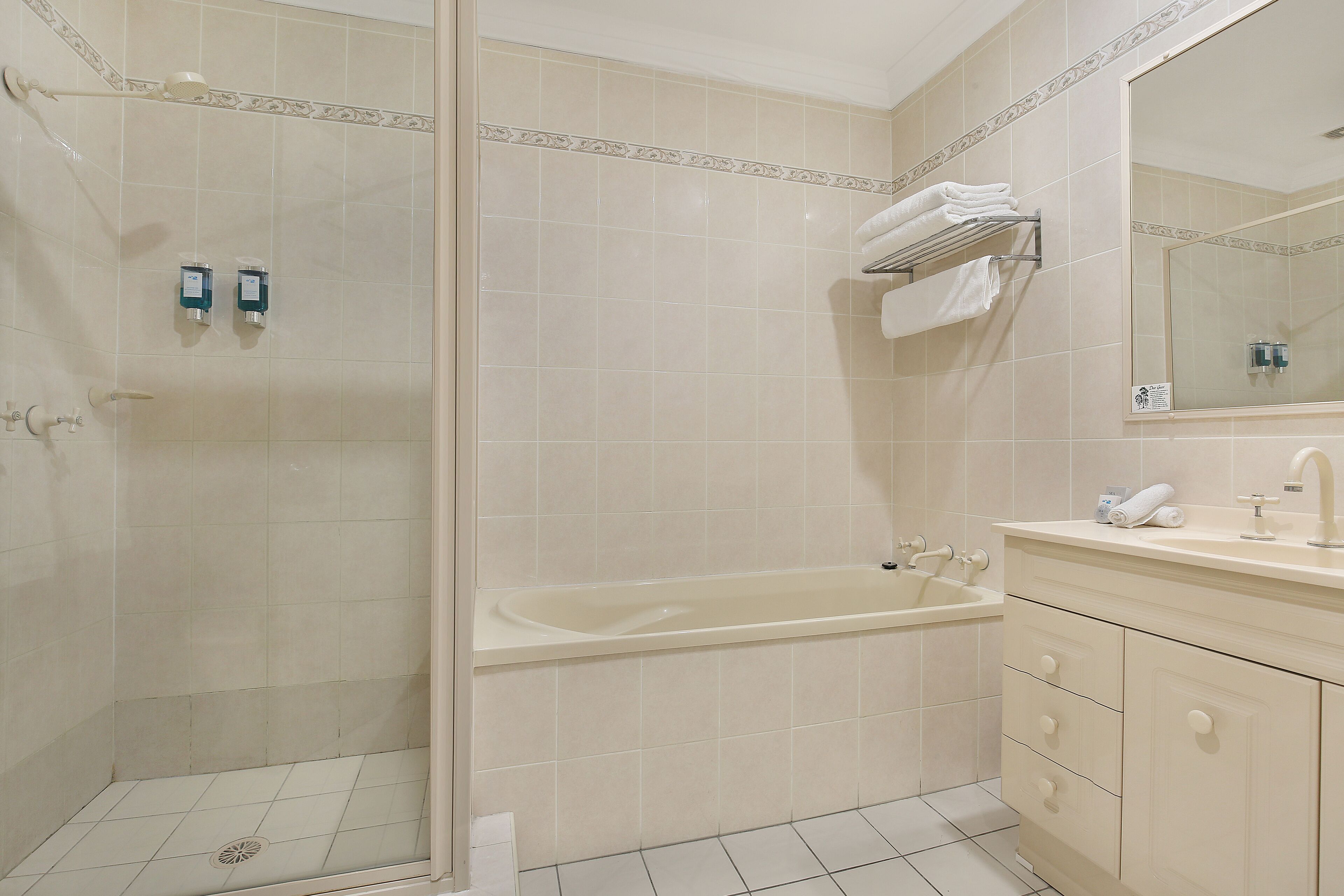 A bathroom with a shower, bathtub, and vanity with a mirror.