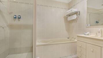 Une salle de bain équipée d’une douche, d’une baignoire et d’un meuble-lavabo avec un miroir.