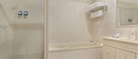 Une salle de bain équipée d’une douche, d’une baignoire et d’un meuble-lavabo avec un miroir.