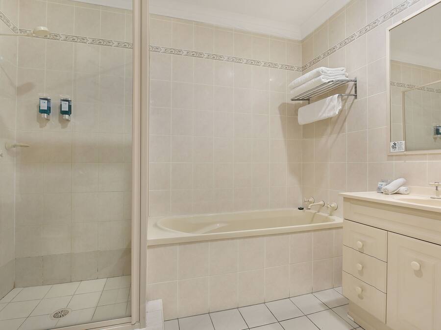 Ein Badezimmer mit Dusche, Badewanne und Waschtisch mit Spiegel.