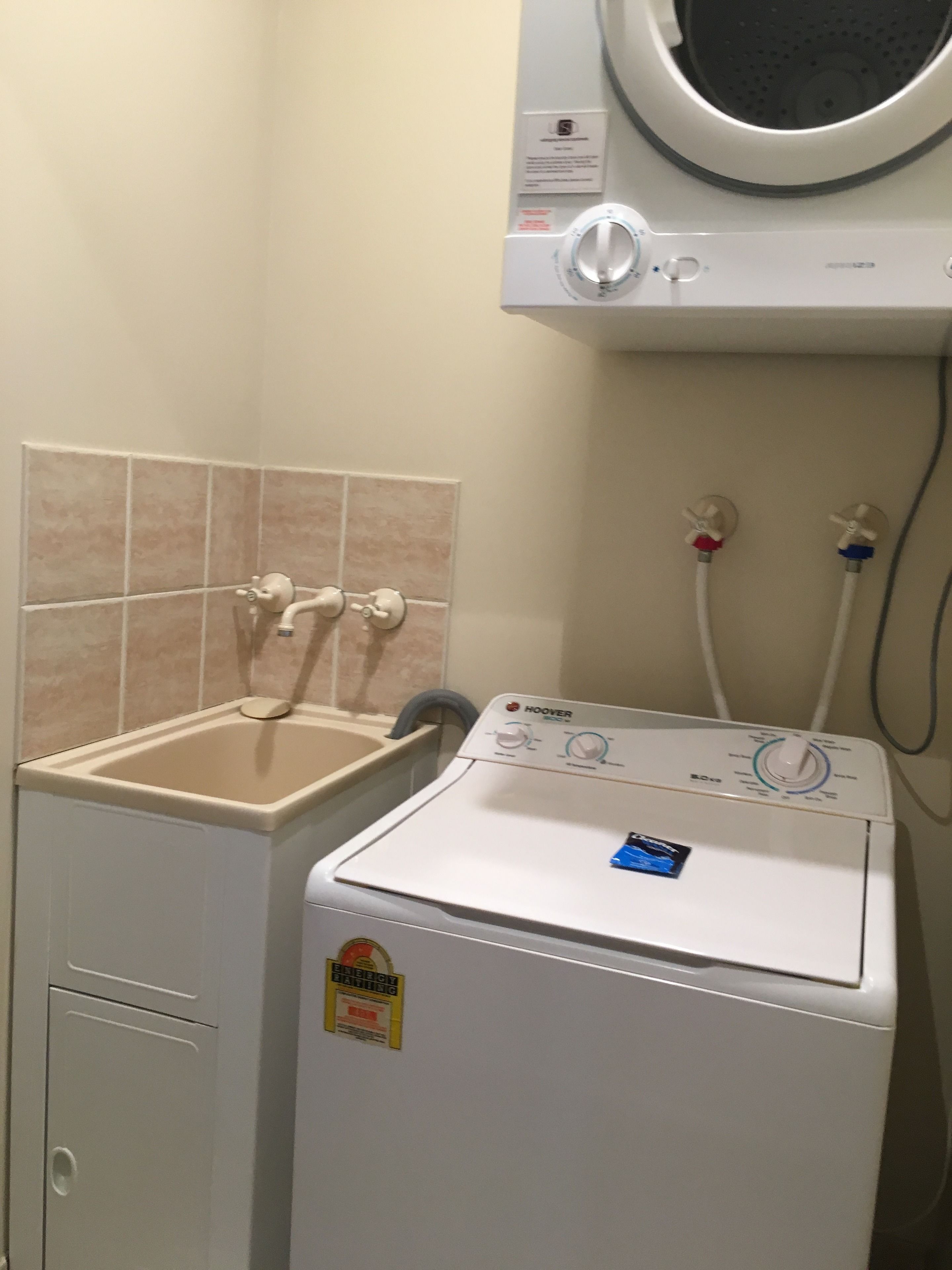 A compact laundry area with a washing machine, a sink, and a towel rack.