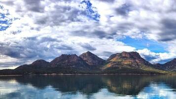 Una cordillera reflejada en aguas tranquilas bajo un cielo nublado.