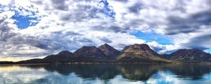 A mountain range reflected in calm water under a cloudy sky. - Gumnut Cottage (Coles Bay)