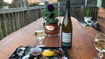 A wooden table with a bottle of wine, a glass, and a tray of oysters and seafood.