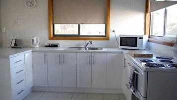 Una cocina equipada con un fregadero, un microondas, una tetera y una estufa.