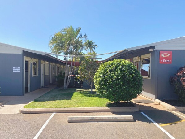 A hotel with a sign indicating 'Hotel Guests Only' and a 'No Trespassing' sign. There is a small lawn area with a bush and a palm tree. - Econo Lodge Karratha (Millars Well)