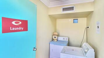 A laundry room with a blue door labeled "Laundry," a washing machine, a dryer, and a small window.
