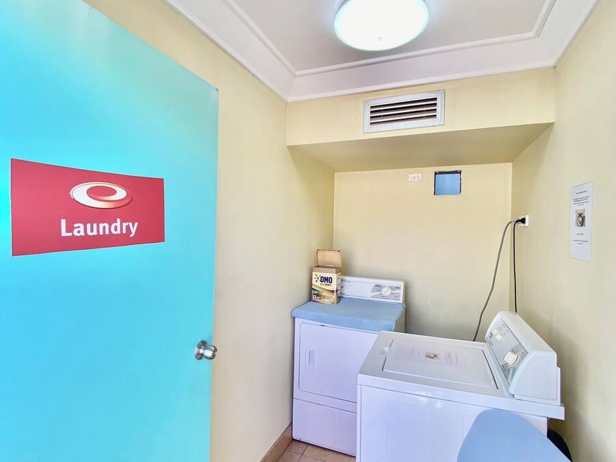 A laundry room with a blue door labeled "Laundry," a washing machine, a dryer, and a small window.