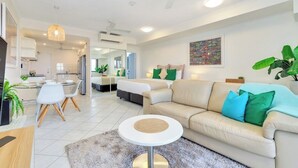 Una sala moderna con un sofá color beige, una mesa redonda de centro y una zona de comedor con sillas blancas.