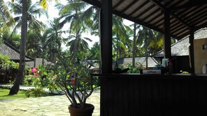 A covered outdoor area with a potted plant, a sign labeled "Office," and a thatched-roof building in the background. - Trawangan Oasis (Gili Trawangan)