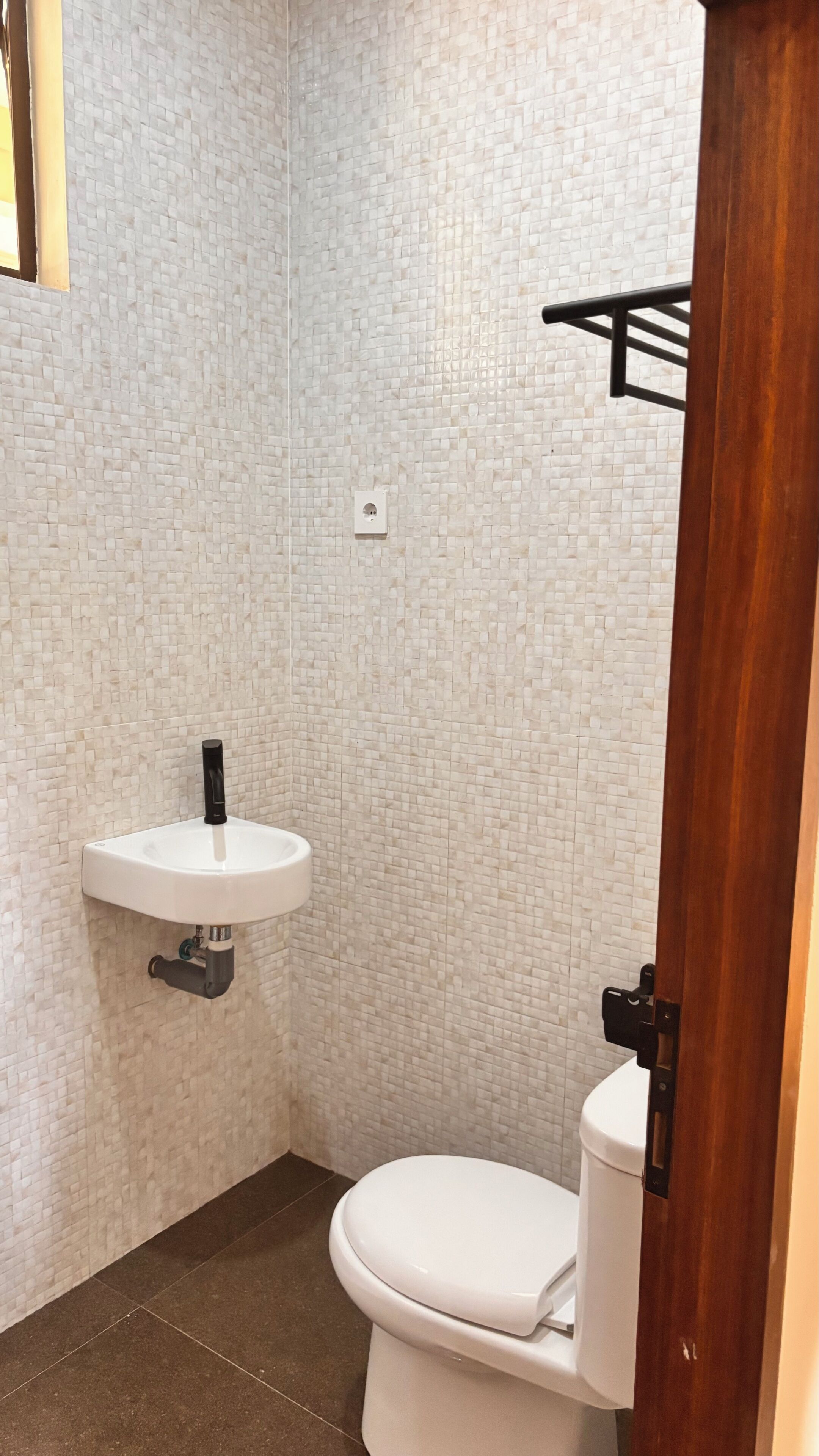 Un baño pequeño con un inodoro blanco, un lavamanos blanco y una pared con azulejos.