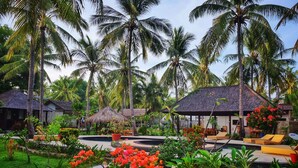 A resort with multiple overwater bungalows, a swimming pool, and lush tropical vegetation. - Trawangan Oasis (Gili Trawangan)